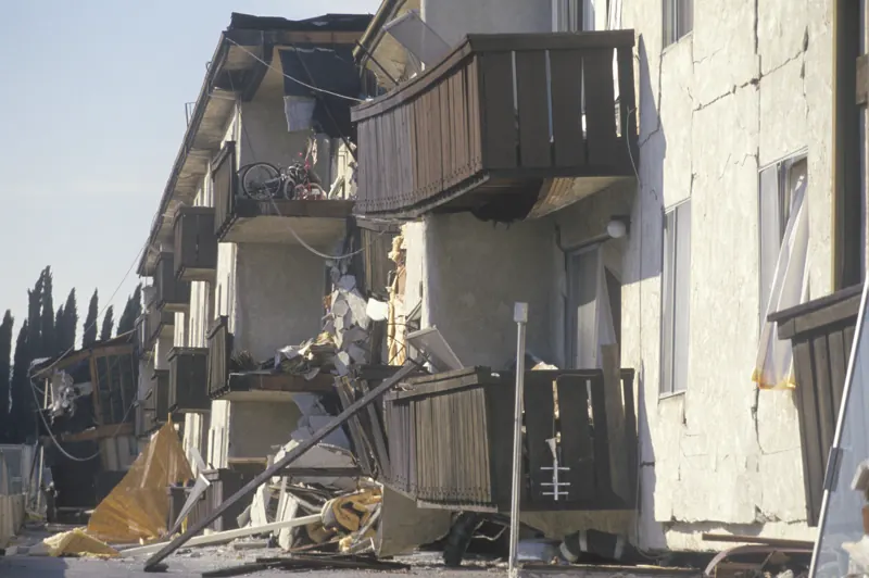 A multi-storey apartment building with its ground floor crushed and upper balconies collapsed after an earthquake
